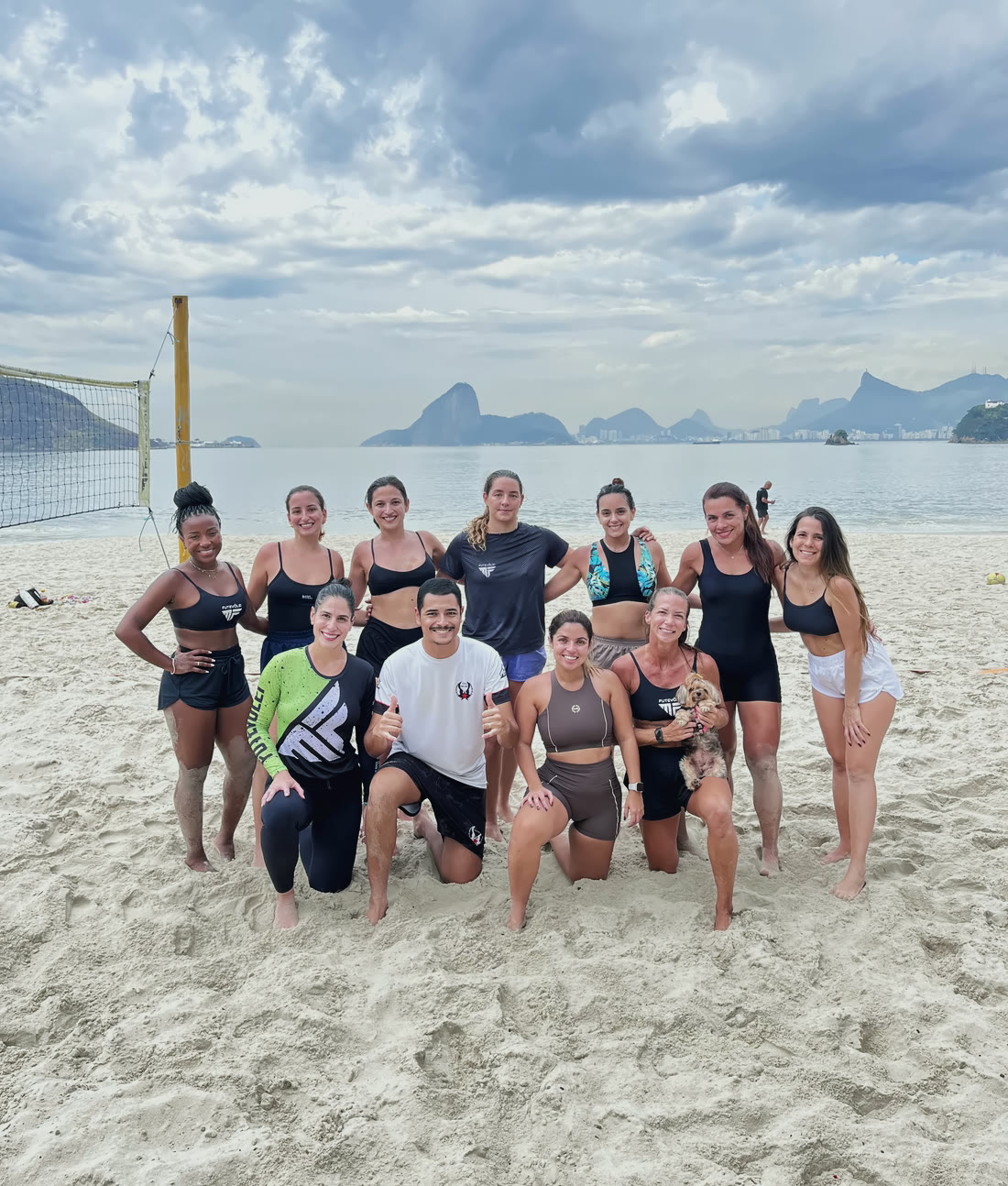 Turma feminina da MF reunida na areia, com o Pão de Açúcar ao fundo